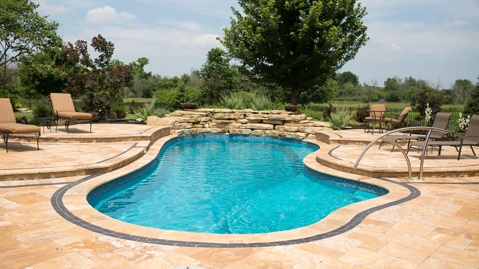 Freeform fiberglass pool beside a landscaped deck