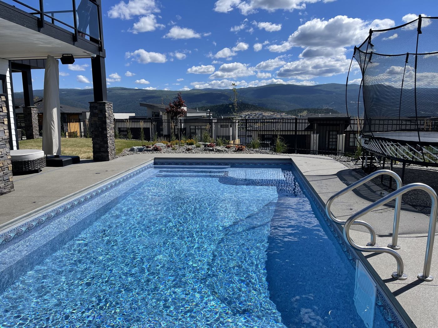 Pool with a trampoline beside it and a view across the valley
