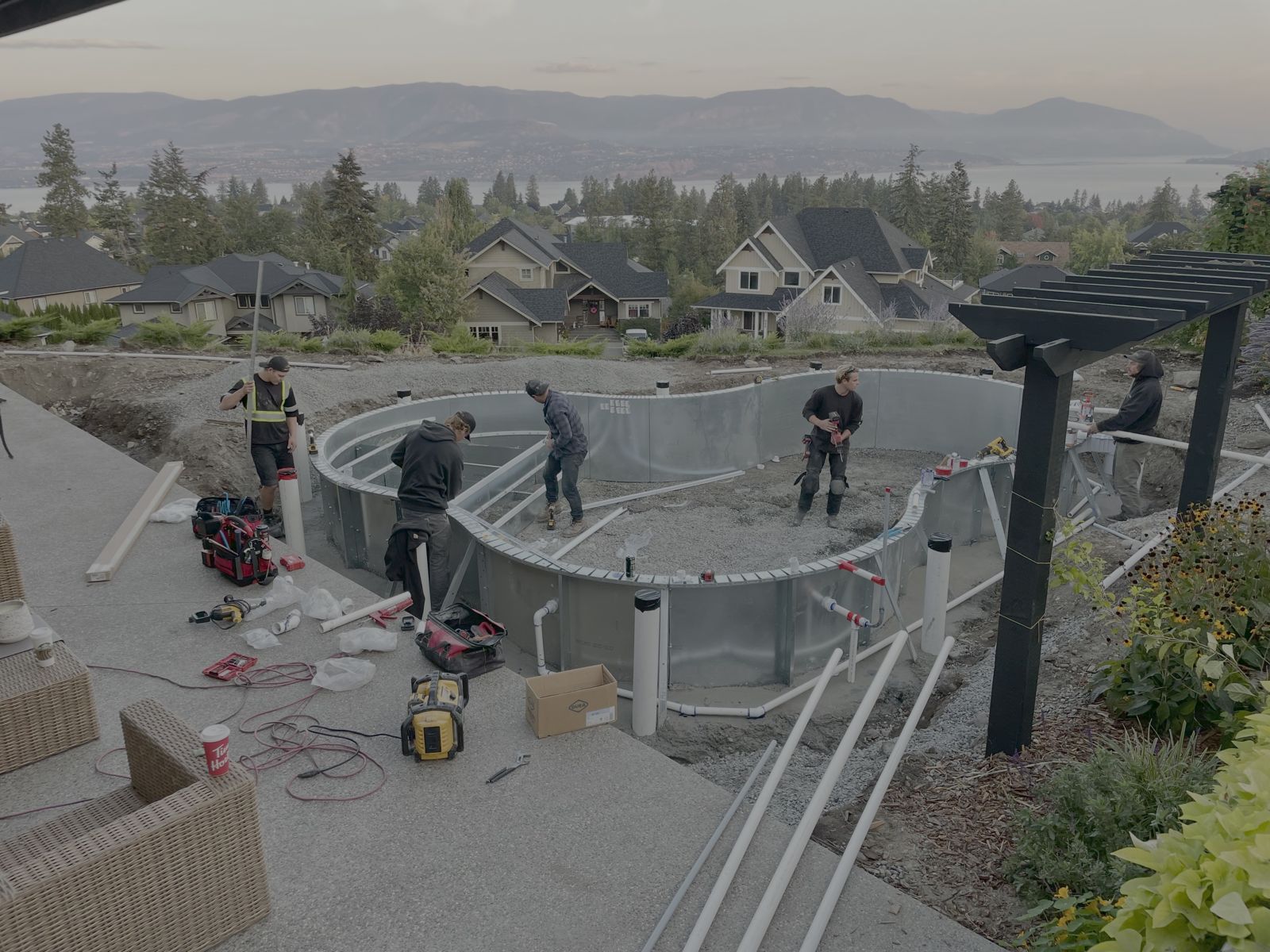 Crew setting pool wall panels on a hillside lot above the lake