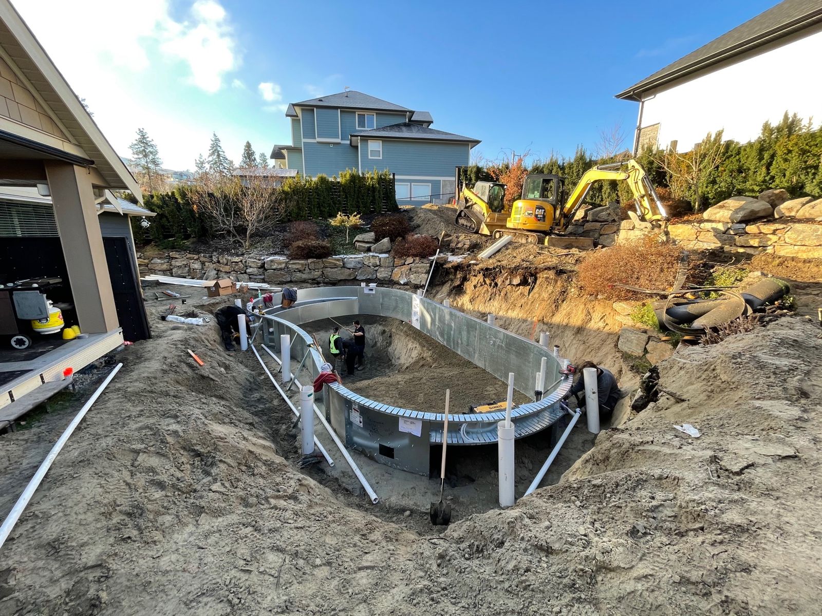 Pool walls and plumbing in an excavation next to a house